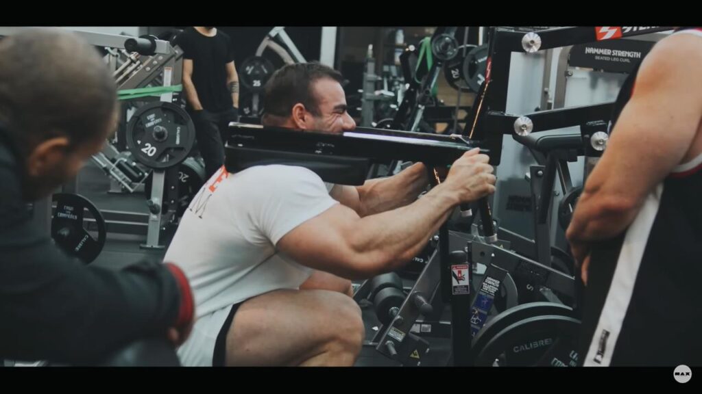 atleta Rafael Brandão fazendo exercício de agachamento squat em aparelho