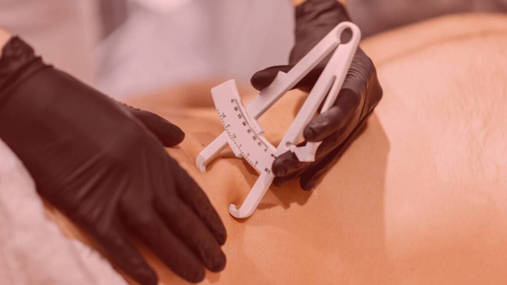 Profissional medindo a gordura corporal com aparelho especializado
