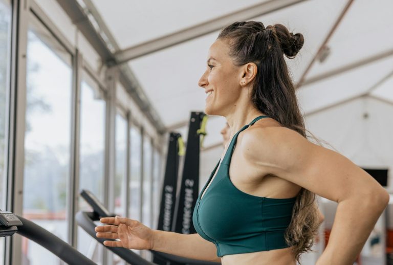 Fit woman jogging on treadmill in an airy gym, focused on health and fitness.