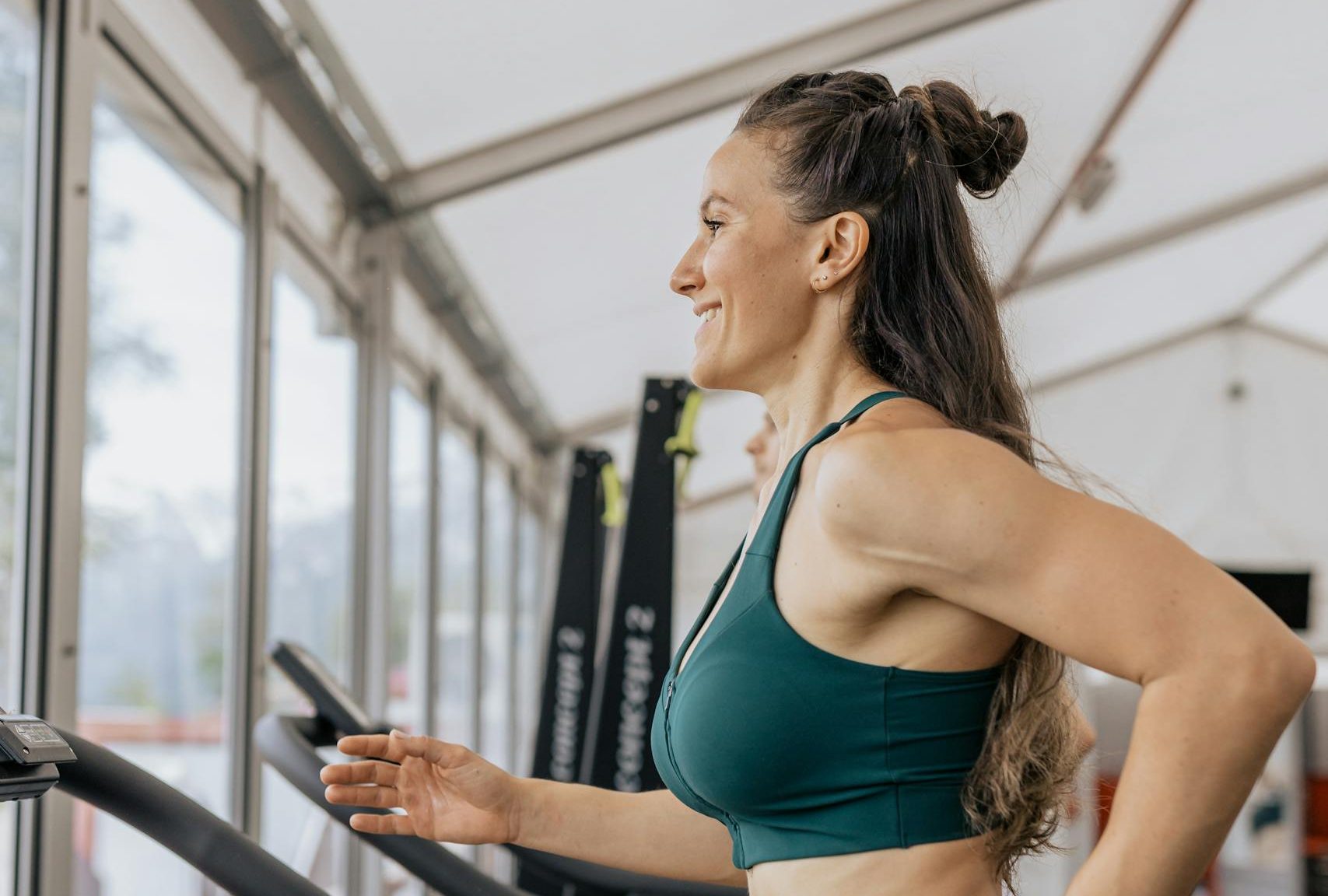 Fit woman jogging on treadmill in an airy gym, focused on health and fitness.